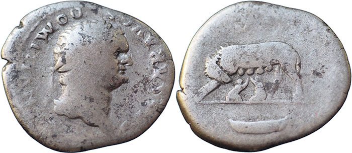 Domitian AR Denarius – COS V above – Wolf and twins left, boat in exergue – RSC 51